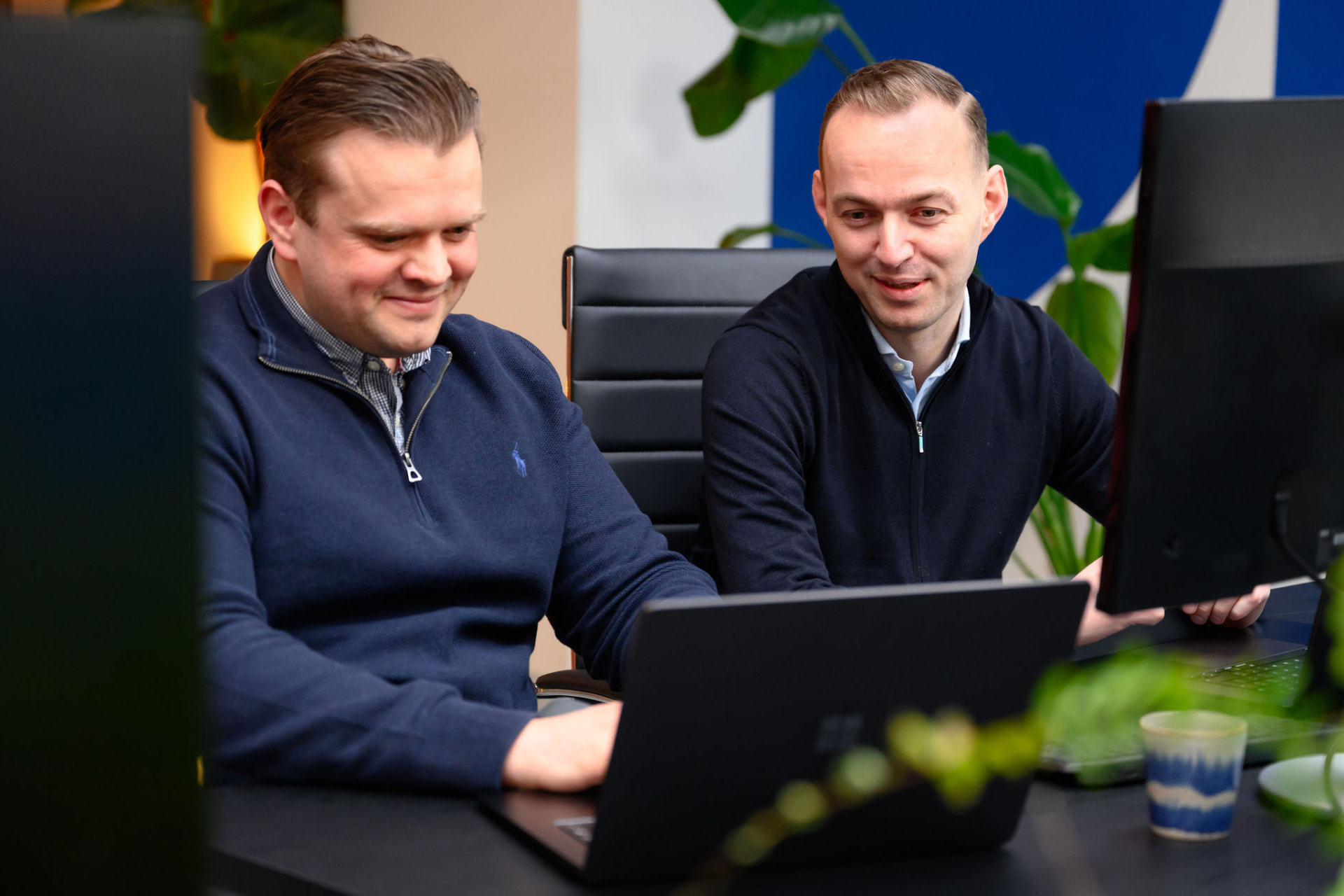 Floris Verschuuren en Lennart Dorsman kijken samen naar een dashboard op kantoor in Den Haag